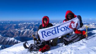 hikers with red fox banner on top of a mountain